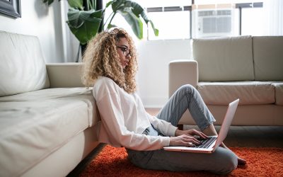 This article is about the advantages and disadvantages of outsourcing with examples and this is a photo of a woman sitting in her living room working on her laptop