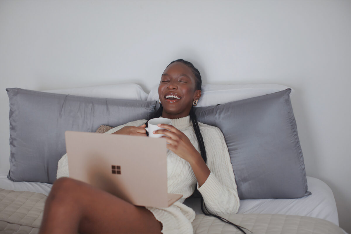 A Black business owner sits back on her bed rejoicing, because she was able to find and pitch meaningful collabs with other entrepreneurs.